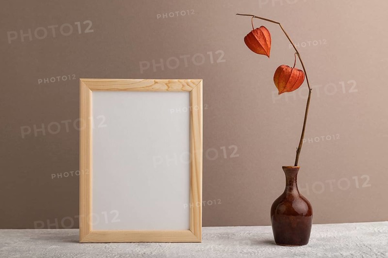White wooden frame mockup with physalis in ceramic vase on beige paper background. Blank, vertical orientation, still life, copy space