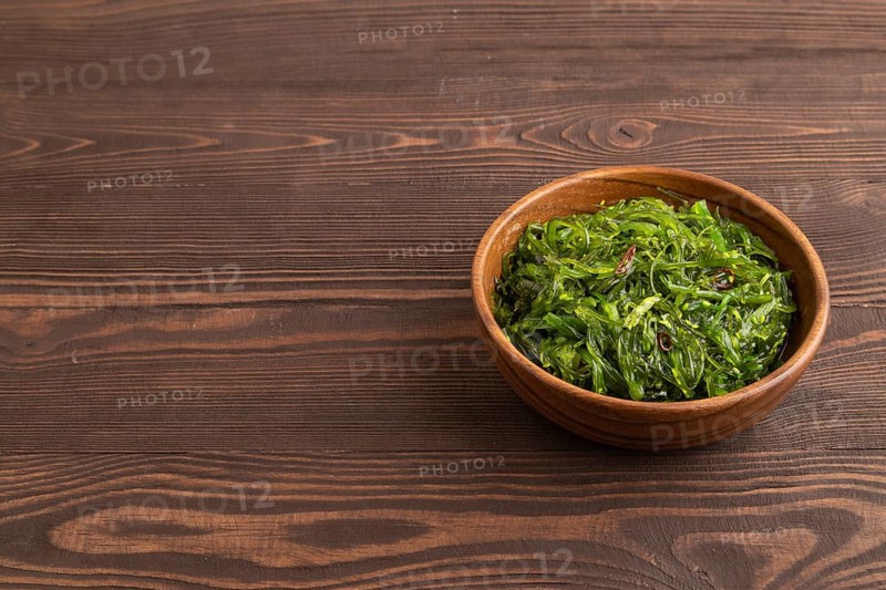 Chuka seaweed salad in wooden bowl on brown wooden background. Side view, copy space