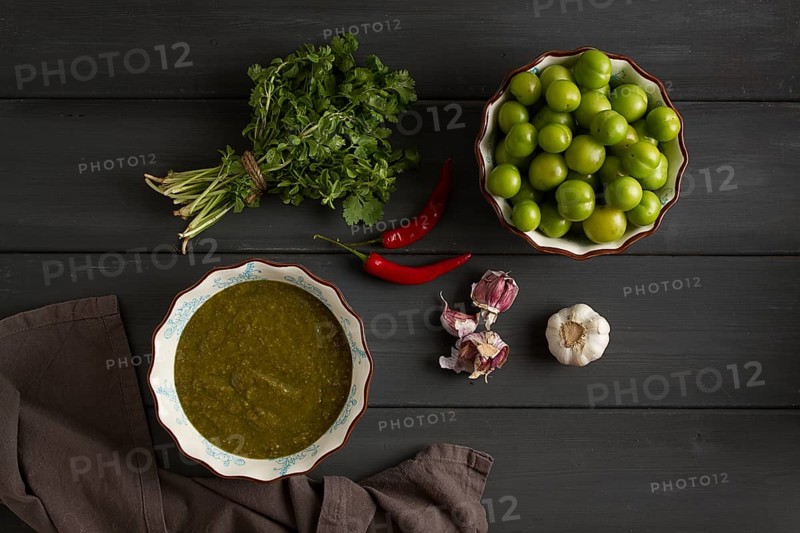 Tkemali sauce, traditional Georgian cuisine, green cherry plum, with ingredients for sauce, cilantro, mint, hot pepper, garlic, on a wooden table, close-up, rustic, food background, no people, selective focus, sauce, green sauce, tkemali, georgian cuisine, homemade