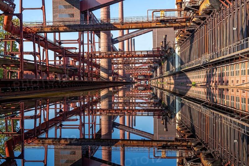 Zollverein coking plant, coke ovens, chimneys and conveyor bridges are reflected in the water basin, which lies between the tracks of the printing machine, for pushing the finished coke out of the ovens, Essen North Rhine-Westphalia, Germany, Europe