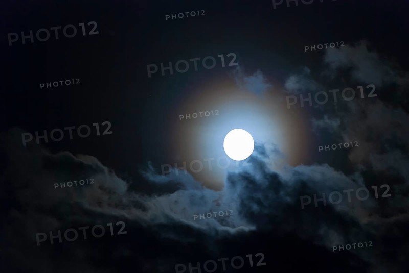 The full moon shines brightly in a cloudy, stormy, black sky and has a halo in rainbow colours (corona, halo), fairytale-like, mystical night shot, dark, somewhat creepy mood, ghostly, symbolic image for fear, nightmare, horror, fantasy, motion blur, wipe effect, Mecklenburg-Western Pomerania, Germany, Europe