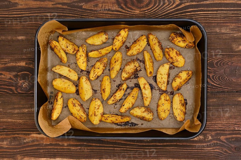 Top view of potato wedges baked in oven in baking tray