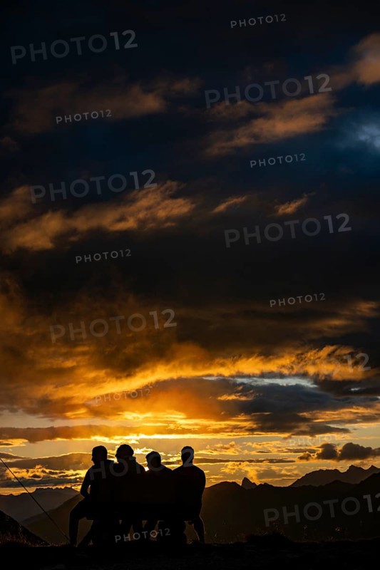 People marvelling at Montafon mountains with dramatic cloudy sky at sunset, Tschagguns, Rätikon, Montafon, Vorarlberg, Austria, Europe