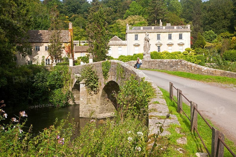 Bridge crossing the River Frome and the classical Georgian facade of Iford Manor, near Freshford, Wiltshire, England, United Kingdom, Europe