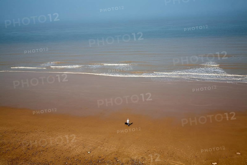 Overhead oblique view of a man walking across wide sandy beach at low tide, Overstrand, Norfolk, England, United Kingdom, Europe