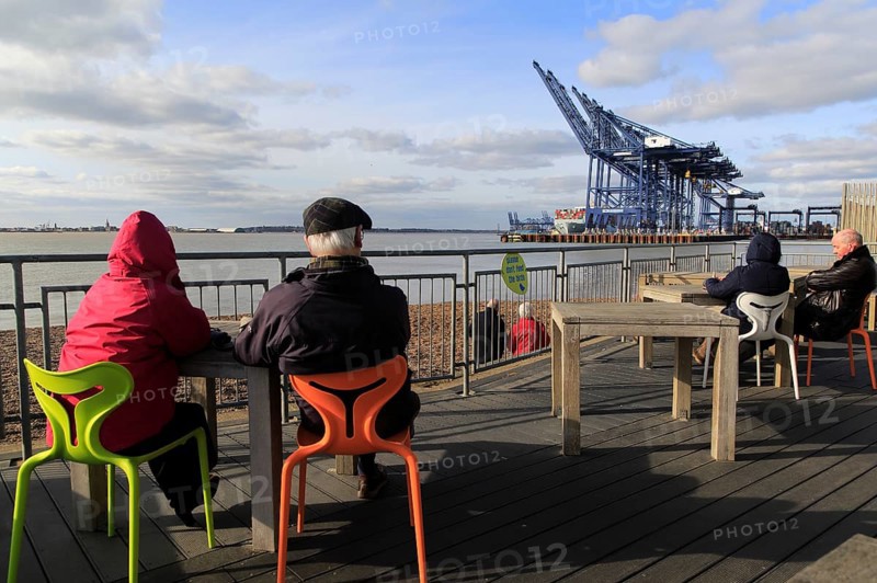 People sitting outside cafe viewing area for Port of Felixstowe, Suffolk, England, UK