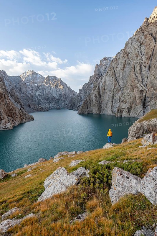 Tourist at the blue mountain lake between rocky steep mountain peaks, Kol Suu Lake, Sary Beles Mountains, Naryn Province, Kyrgyzstan, Asia