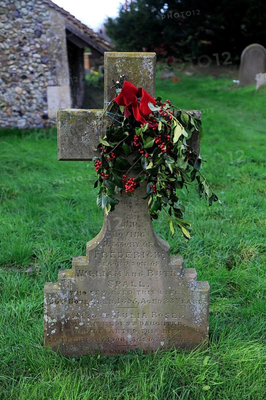 Family headstone in church graveyard decorated with holly for Christmas, Shottisham, Suffolk, England, UK