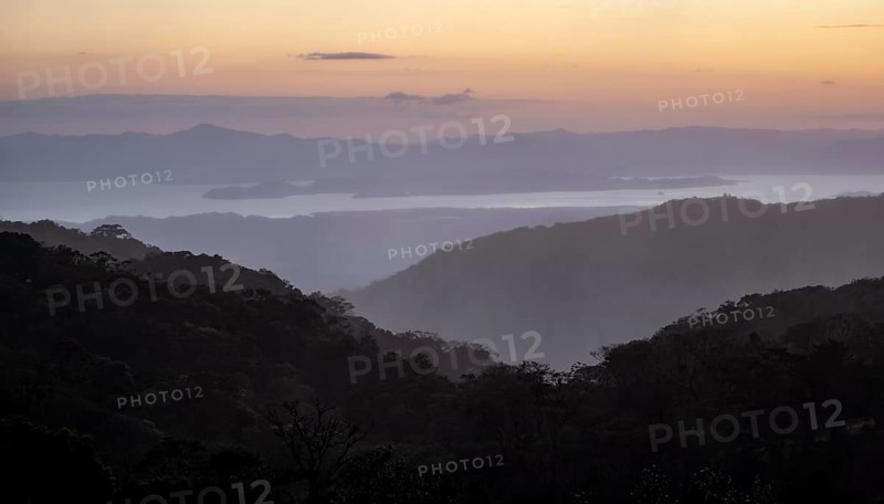 View to the sea over wooded hills, at sunset, cloud forest, Monte Verde, Puntarenas province, Costa Rica, Central America