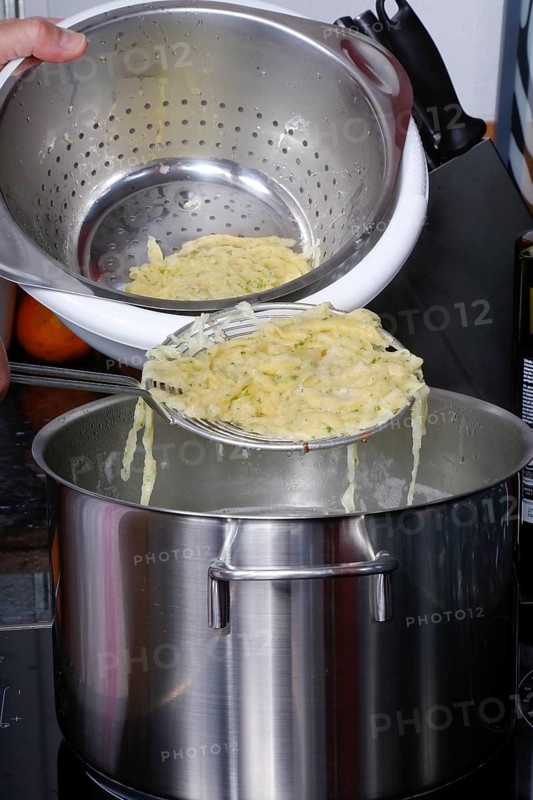 Swabian cuisine, preparation of herb spaetzle for roast beef, scooping spaetzle from boiling water, cooking pot, slotted spoon, spaetzle scoop, savoury, salty, typical Swabian, home cooking, traditional cuisine, men's thumb, food photography, studio, Germany, Europe