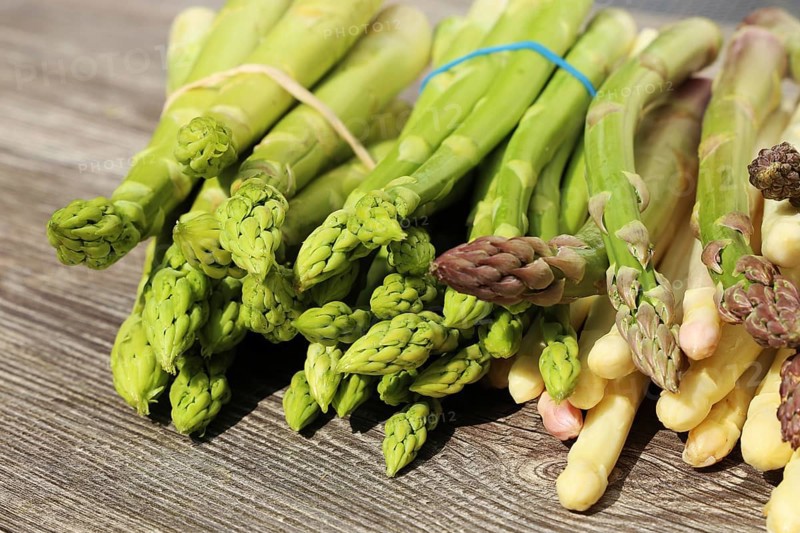 Green asparagus and white asparagus decorated on a rustic wooden table