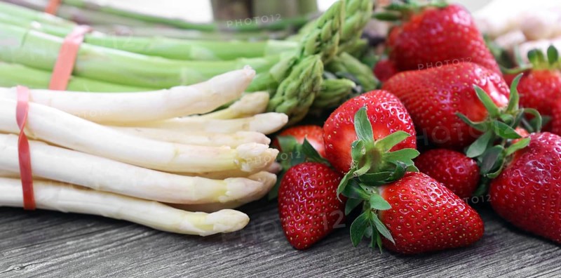 Green asparagus, white asparagus and fresh strawberries decorated on a rustic wooden table
