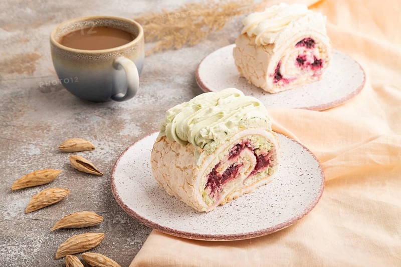 Roll biscuit cake with cream cheese and jam, cup of coffee on brown concrete background and orange linen textile. side view, close up
