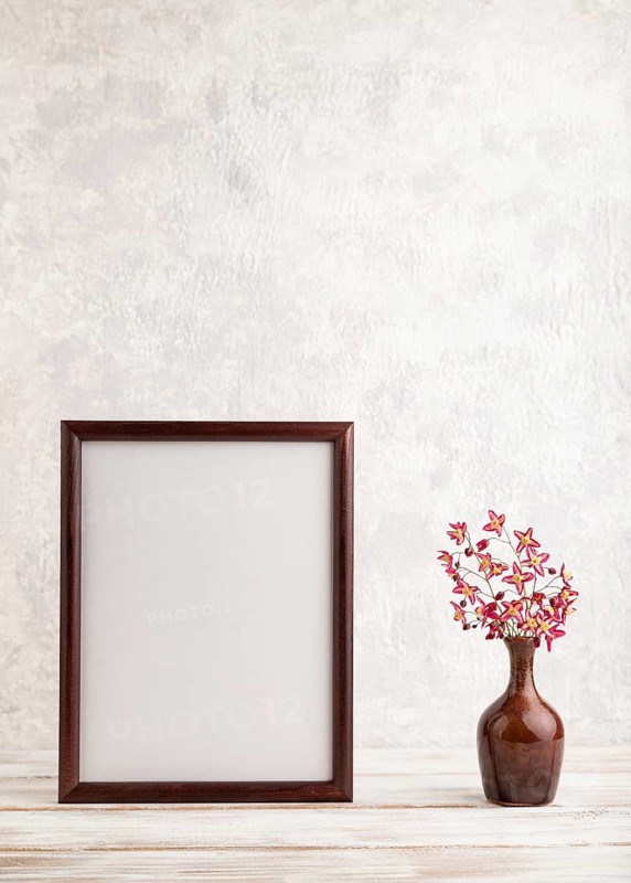 Wooden frame with purple barrenwort flowers in ceramic vase on gray concrete background. side view, copy space, still life, mockup, template, spring, summer minimalism concept