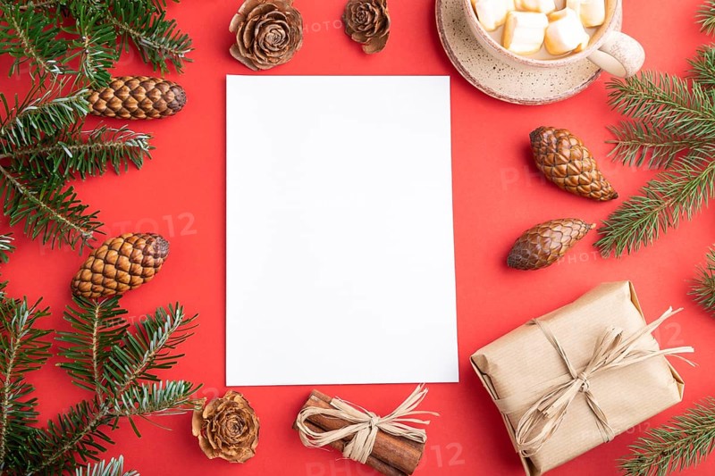 Christmas or New Year frame composition, template. Decorations, box, cinnamon, cones, fir and spruce branches, cup of coffee, on a red paper background. Top view, copy space, flat lay