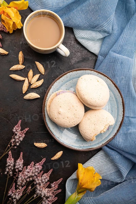 Meringues cakes with cup of coffee on a black concrete background and blue linen textile. Top view, flat lay, close up