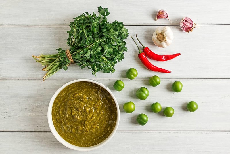 Tkemali sauce, traditional Georgian cuisine, green cherry plum, with ingredients for sauce, cilantro, mint, hot pepper, garlic, on a white wooden table, close-up, rustic, food background, no people, selective focus, sauce, green sauce, tkemali, georgian cuisine, homemade