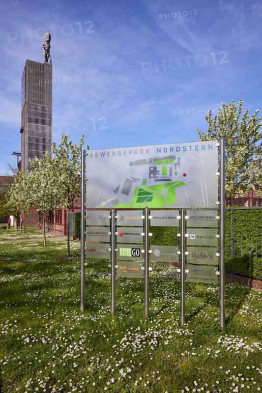 Signpost to the companies in the Nordstern industrial park and the winding tower of Nordstern colliery with the statue of Hercules in Nordsternpark, Gelsenkirchen, Ruhr area, independent city, North Rhine-Westphalia, Germany, Europe