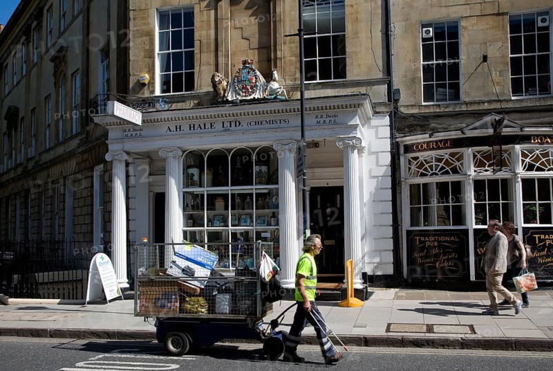 Street cleaner pulling a rubbish collection cart in Argyle Street, Bath, Somerset, England, United Kingdom, Europe