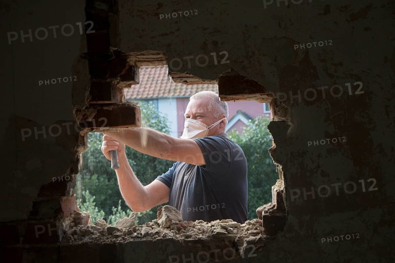 Builder removing red bricks to make window space, Suffolk, England, UK