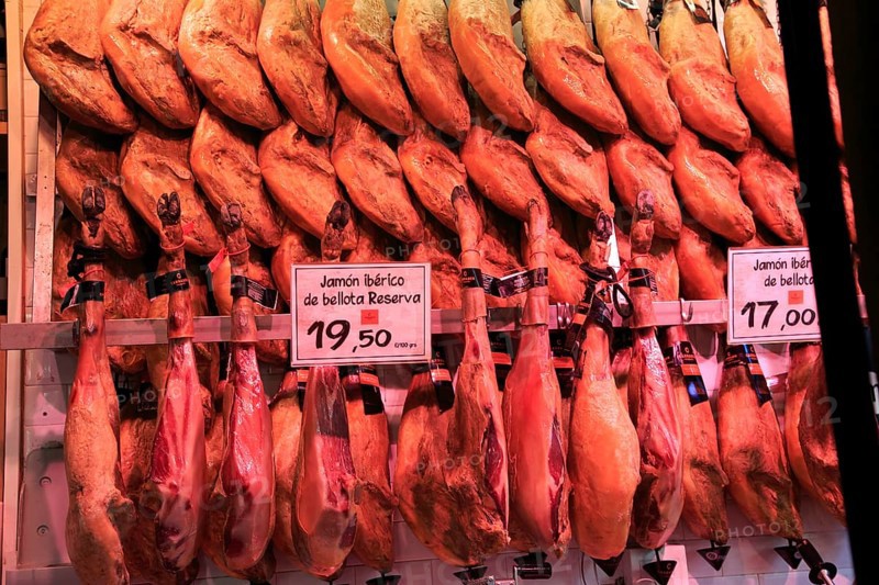 Meat stall butcher selling Jamon Iberico joints, Mercado de San Miguel market, Madrid city centre, Spain, Europe