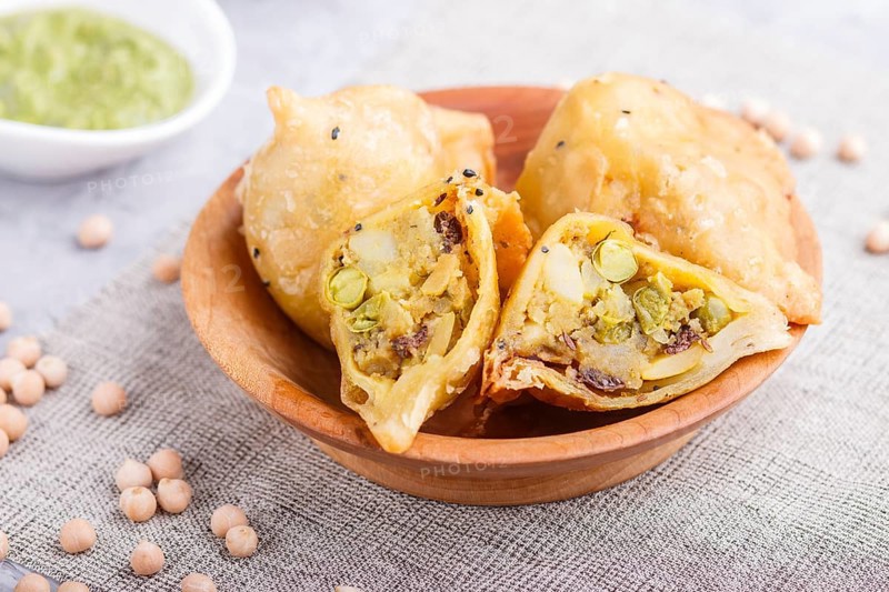 Traditional indian food samosa in wooden plate with mint chutney on a gray concrete background. side view, close up