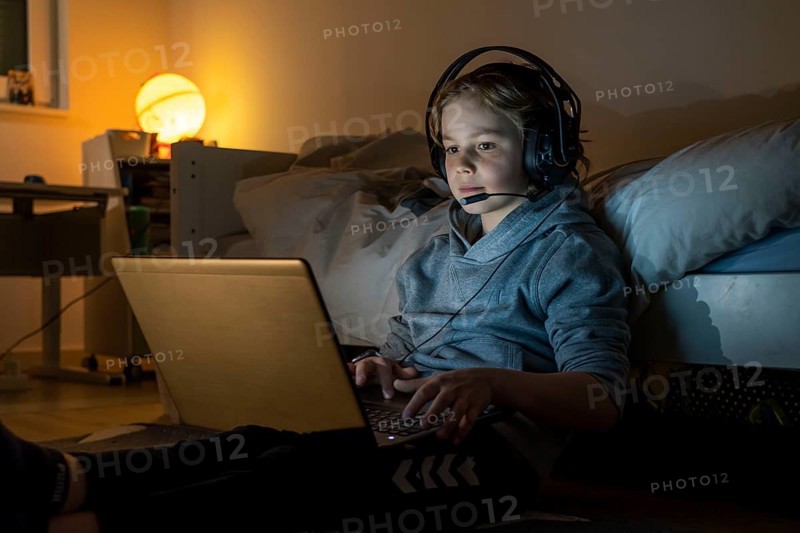 Boy, at home on the computer, laptop, in the children's room, playing a game, chatting with other children, fellow players
