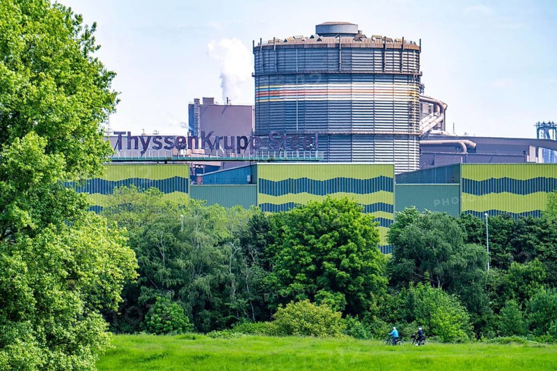 The ThyssenKrupp Steel steelworks in Duisburg-Beeckerwerth, cyclists on the Rhine dyke, green Rhine meadows Landscape, North Rhine-Westphalia, Germany, Europe