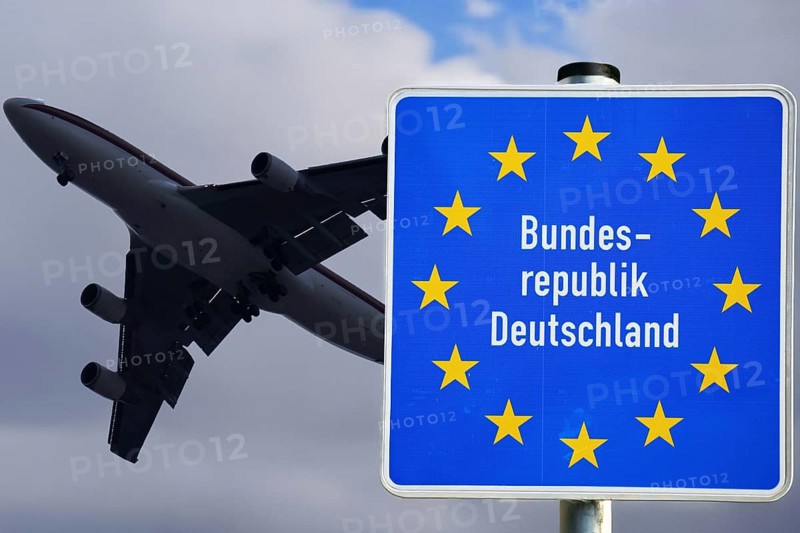 Symbolic image of the asylum debate: A plane taking off next to a border sign of the Federal Republic of Germany (Composing)