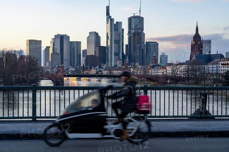 Skyline of the city centre of Frankfurt am Main, cargo bike cyclist on the Ignatz-Bubis-Bridge, dusk, river Main, winter, Hesse, Germany, Europe