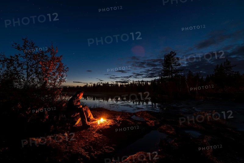 Man in the evening at a bivouac with campfire, Lapland, Sweden, Scandinavia, Europe