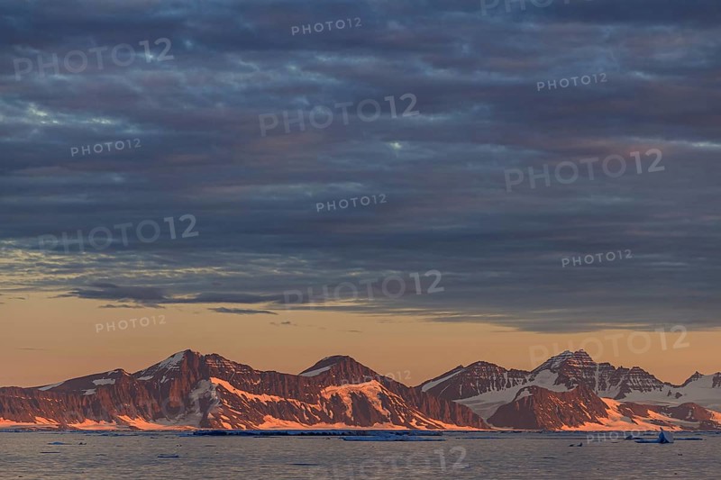 Evening light and atmosphere in fjord with icebergs in front of steep mountains, cloudy, autumn, Ittoqqortoormiit, Scoresby Sund, East Greenland, Greenland, North America