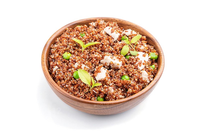 Quinoa porridge with green pea and chicken in wooden bowl isolated on a white background. Side view, close up
