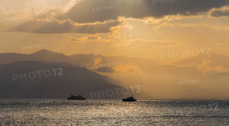 Dramatic sunset over the sea with boat silhouettes and cloudy sky, Agia Kyriaki, Nafplio, Nauplia, Nauplion, Nafplion, Argolis, Argolic Gulf, Peloponnese, Greece, Europe