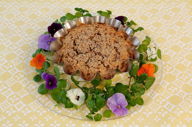 Vegetarian cuisine, chestnut roast, chestnut cake, chestnut roast, chestnut cake with hazelnuts, chestnut cake, hearty, vegan, savoury, baked, from the oven, healthy, main course, cake tin, baking tin, glass plate, new kitchen, decoration with pansies, violet (Viola), food photography, studio, Germany, Europe