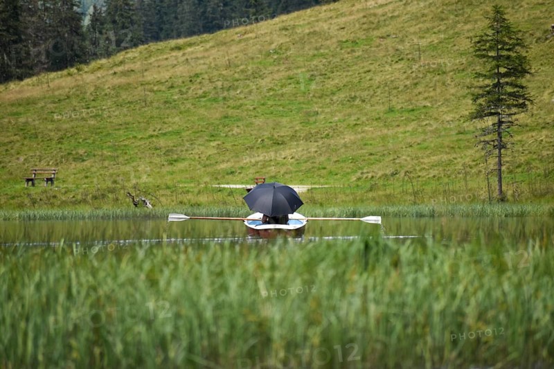Holidaymaker with parasol in a rowing boat on the mountain lake Steirischer Lake Constance, Schladminger Tauern, Styria, Austria, Europe