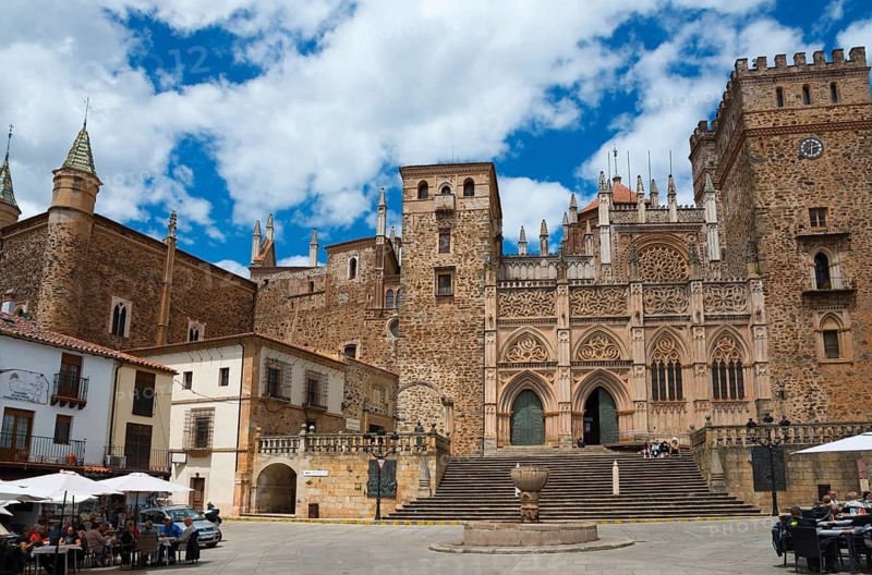 Historisches Steinbauwerk auf einem Platz unter einem leicht bewölkten Himmel, Wallfahrtskirche und Kloster, Real Monasterio de Nuestra Señora de Guadalupe, Guadalupe, Provinz Cáceres, Caceres, Extremadura, Spanien