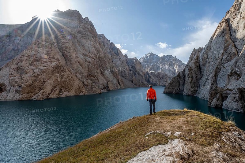 Tourist at the blue mountain lake between rocky steep mountain peaks, Sun Star, Kol Suu Lake, Kurumduk Valley, Sary Beles Mountains, Naryn Province, Kyrgyzstan, Asia