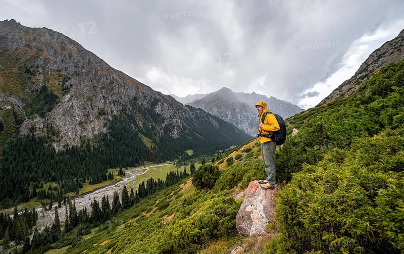Mountaineer on a rock, Green mountain valley with river and steep mountain peaks, Chong Kyzyl Suu Valley, Terskey Ala Too, Tien-Shan Mountains, Kyrgyzstan, Asia
