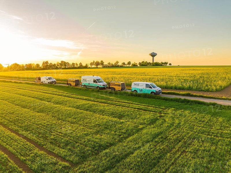 Cars driving along a rural road next to green and blooming fields at sunset, fibreglass installation, Calw district, Black Forest, Germany, Europe