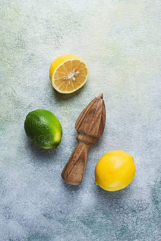 Wooden citrus reamer, manual lemon juicer, made of acacia wood, with citrus fruits on the table, top view