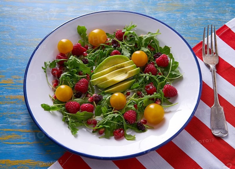 Avocado and berries salad with arugula and yellow cherry tomatoes