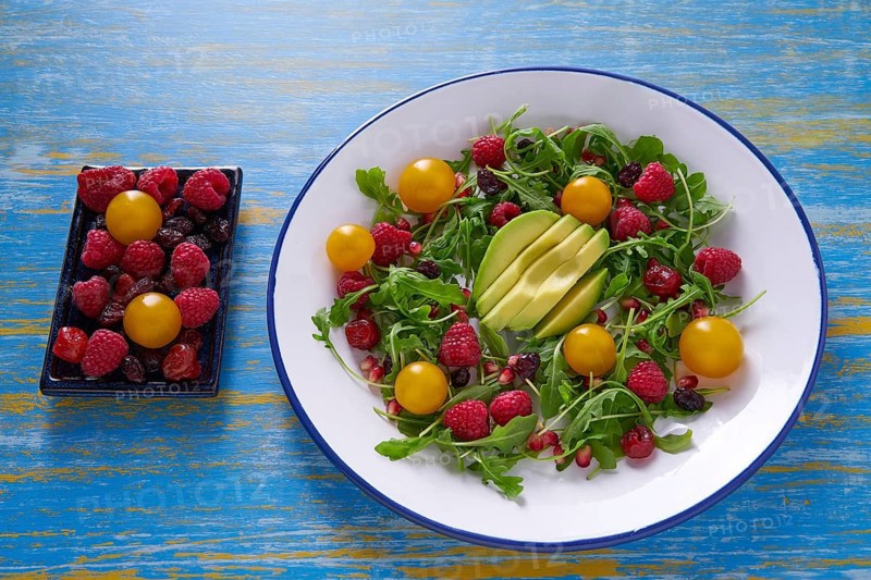 Avocado and berries salad with arugula and yellow cherry tomatoes