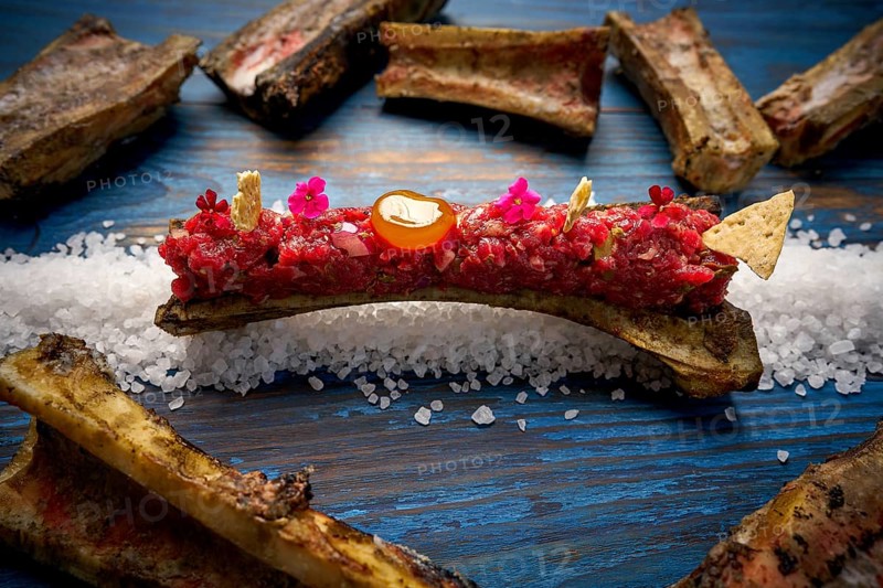 Steak tartar with egg yolk on half bone presentation modern cuisine