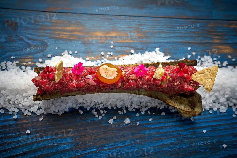 Steak tartar with egg yolk on half bone presentation modern cuisine
