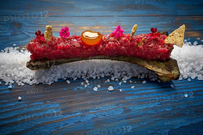 Steak tartar with egg yolk on half bone presentation modern cuisine
