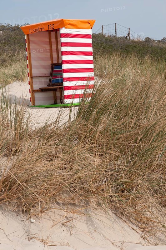 A red and white striped beach chair in front of sandy dunes and grasses, Borkum, l North Sea, GERMANY