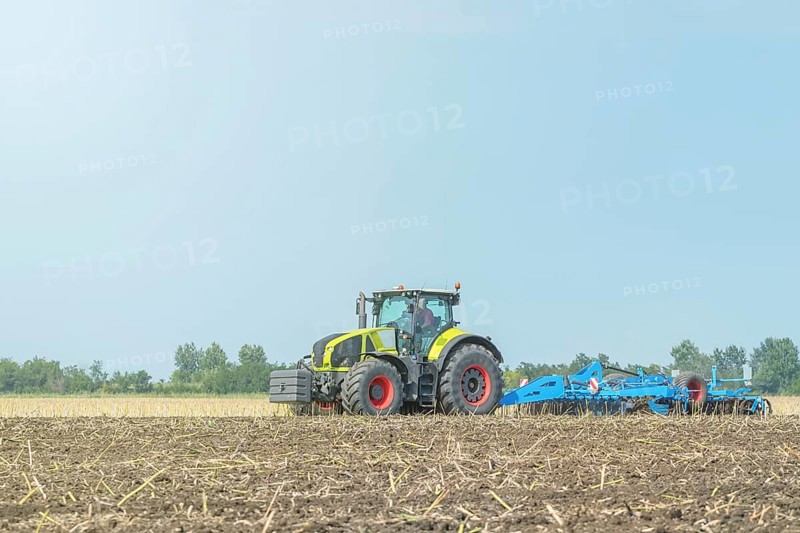 Farmer in tractor preparing land seedbed cultivator. Agriculture tractor landscape