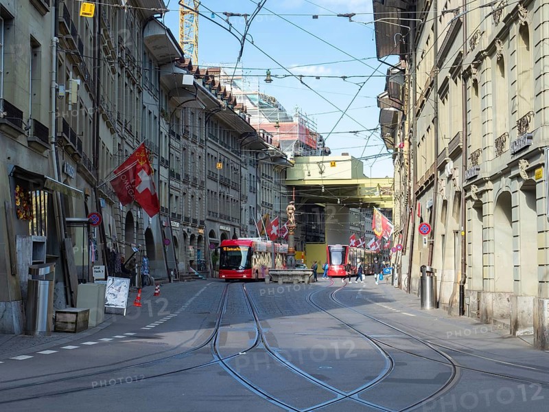 Situation in the historic city centre of Berne, Switzerland. A tramcar and a trolley bus moving along a street with old buildings