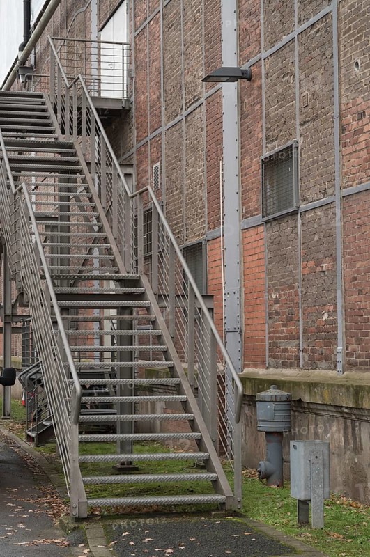 Exterior metal staircase provides access to an industrial building with a brick facade